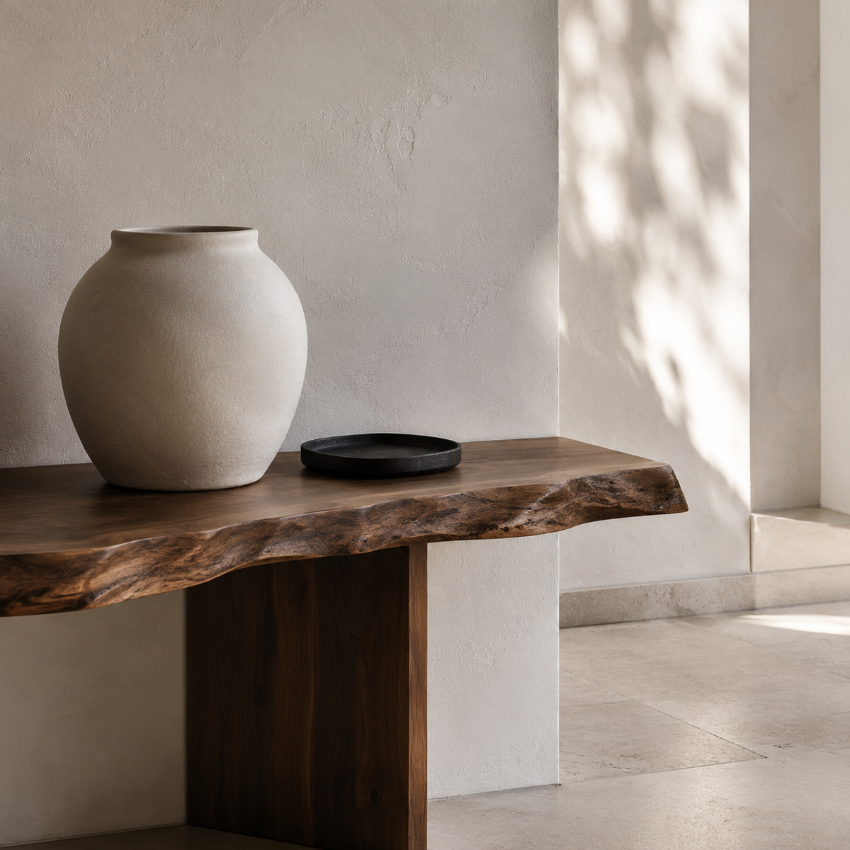 Live-edge walnut console with matte ceramic vessel in natural sunlight